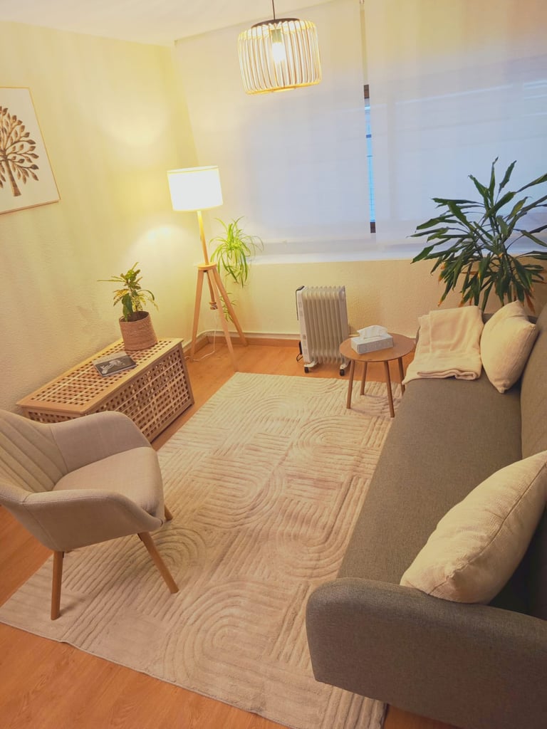 Minimalist living room with gray armchairs, wooden floor, geometric patterned rug, potted plants, floor lamp, and pendant light fixture